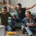 front-view-cheerful-male-friends-watching-sports-tv-together-while-having-snacks-beer